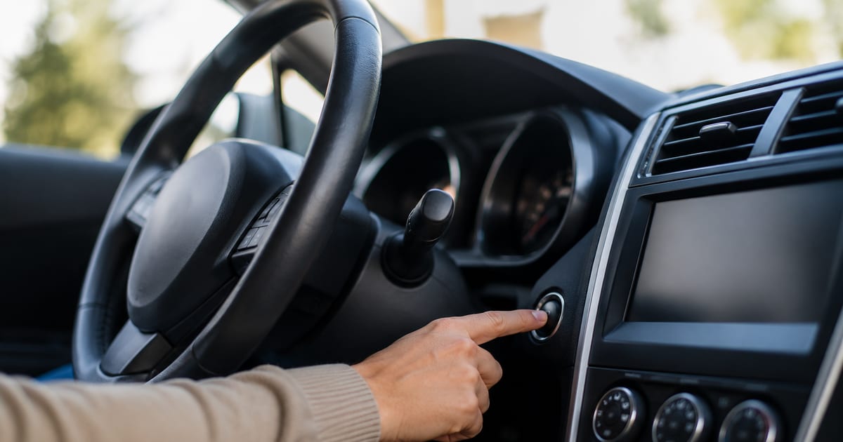 Main tournant une clé de contact dans l'habitacle d'une voiture